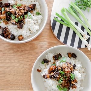 Overhead view of two bowl of eggplant teriyaki served over white rice and garnished with sliced green onion.