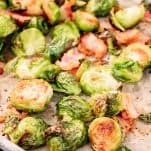 A parchment lined sheet pan of cooked Brussels sprouts with bacon.