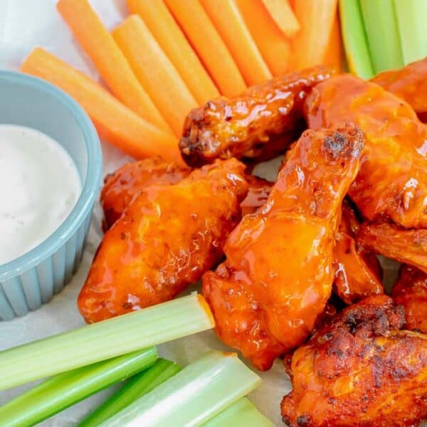 cooked buffalo wings on a platter with raw veggies and dip