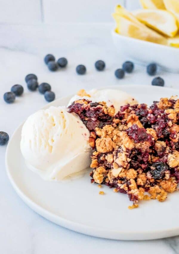 bBueberry crumble shown on a plate with ice cream.
