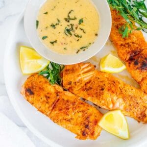 cooked salmon fillets on a plate with a white wine sauce