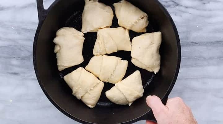 chicken pot pie mixture in a raw crescent rolls wrapped up in a skillet