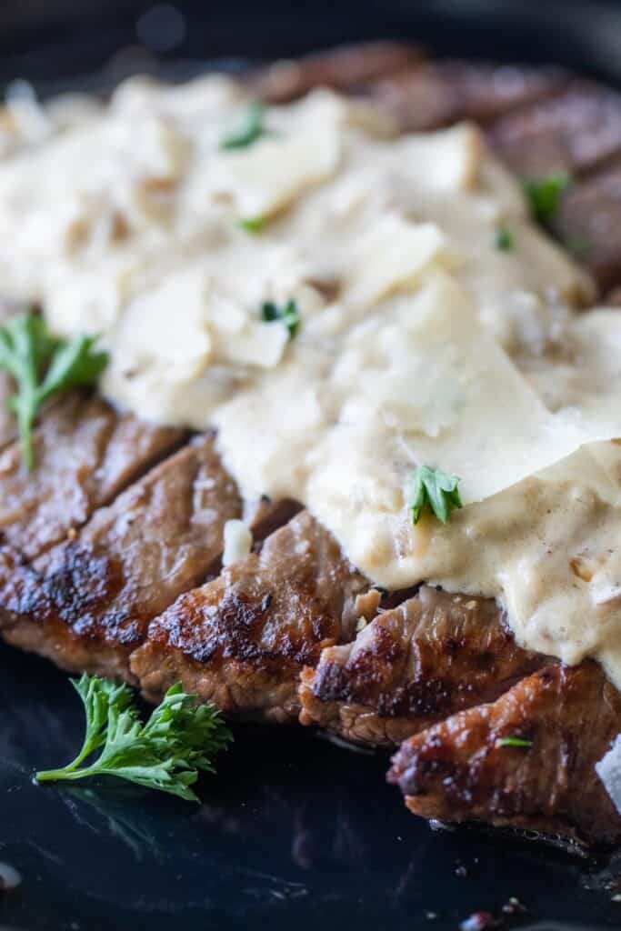 pan seared skirt steak sliced with parmesan cheese sauce on top