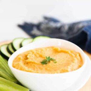 spicy hummus recipe without tahini shown in a white bowl with vegetables