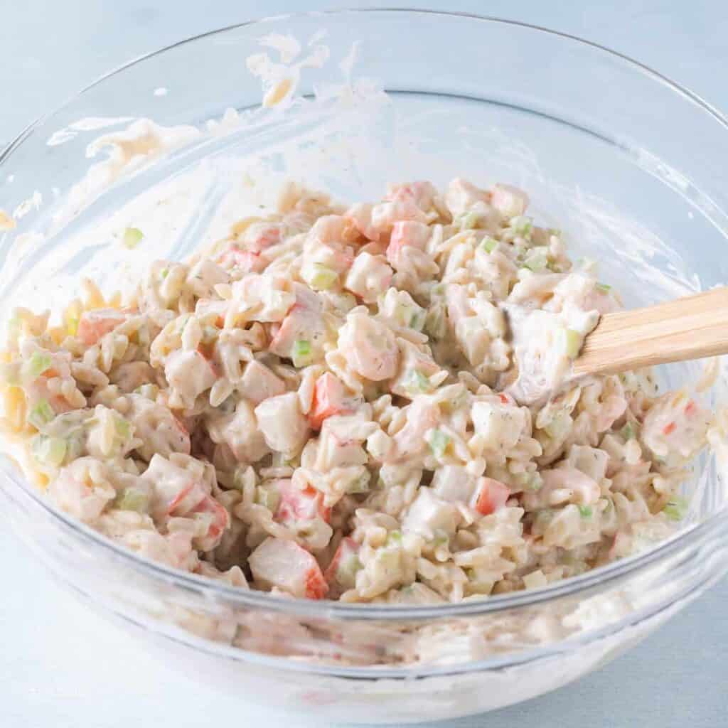 crab pasta salad being made in a bowl