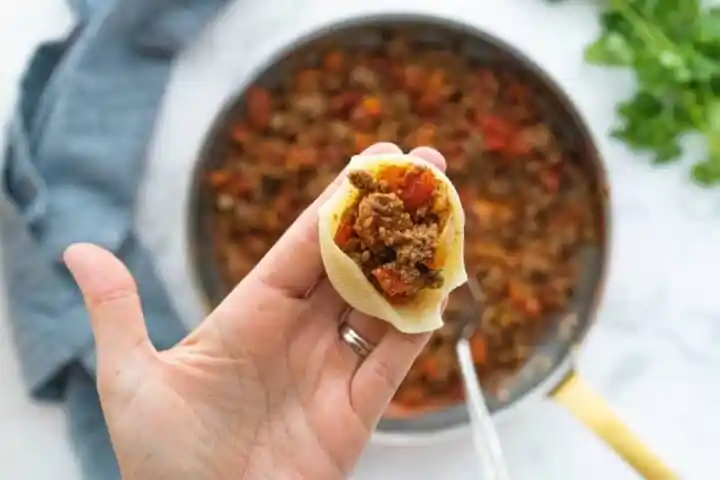 a pasta shell being stuffed with taco meat