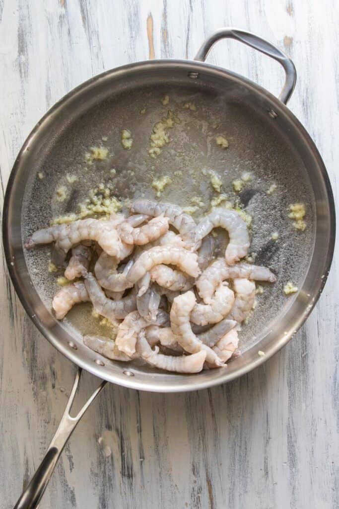 raw shrimp in garlic butter in a skillet