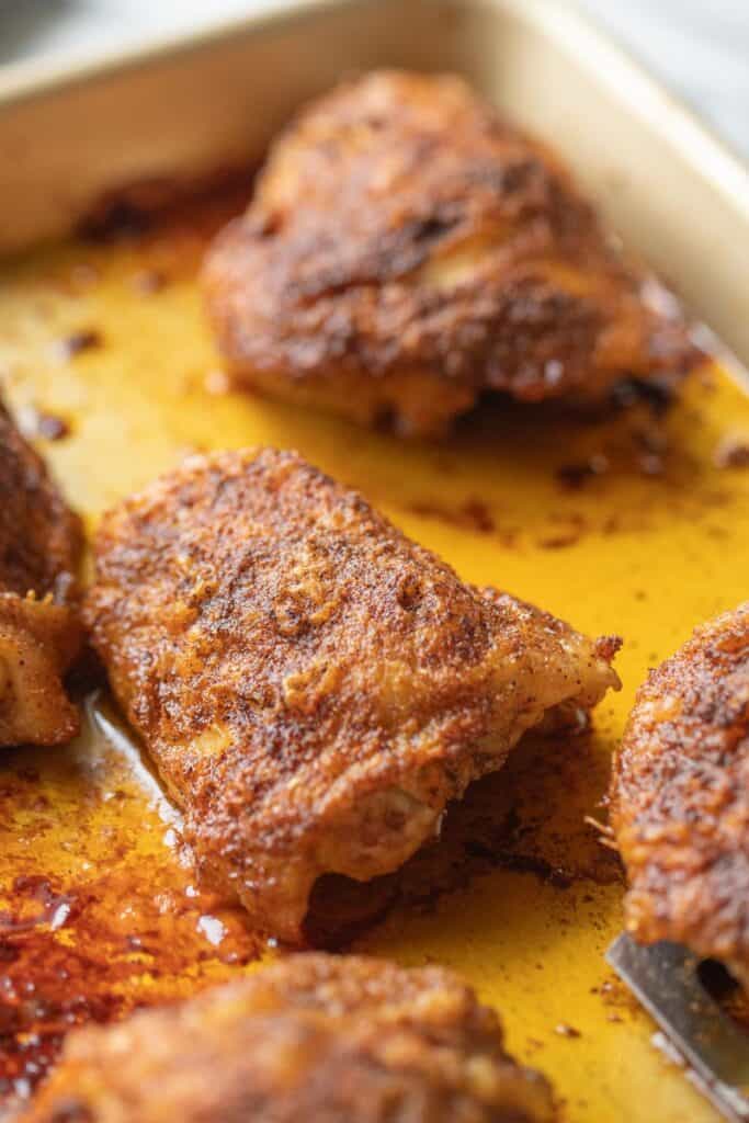 crispy chicken thighs shown on a baking pan