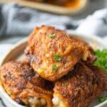 crispy chicken thighs shown on a plate with parsley