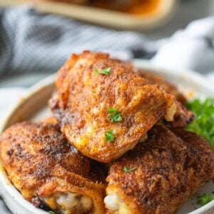 crispy chicken thighs shown on a plate with parsley