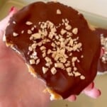 a hand holding a rice cake with peanut butter and chocolate
