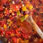 a wooden spoon stirring three bean chili